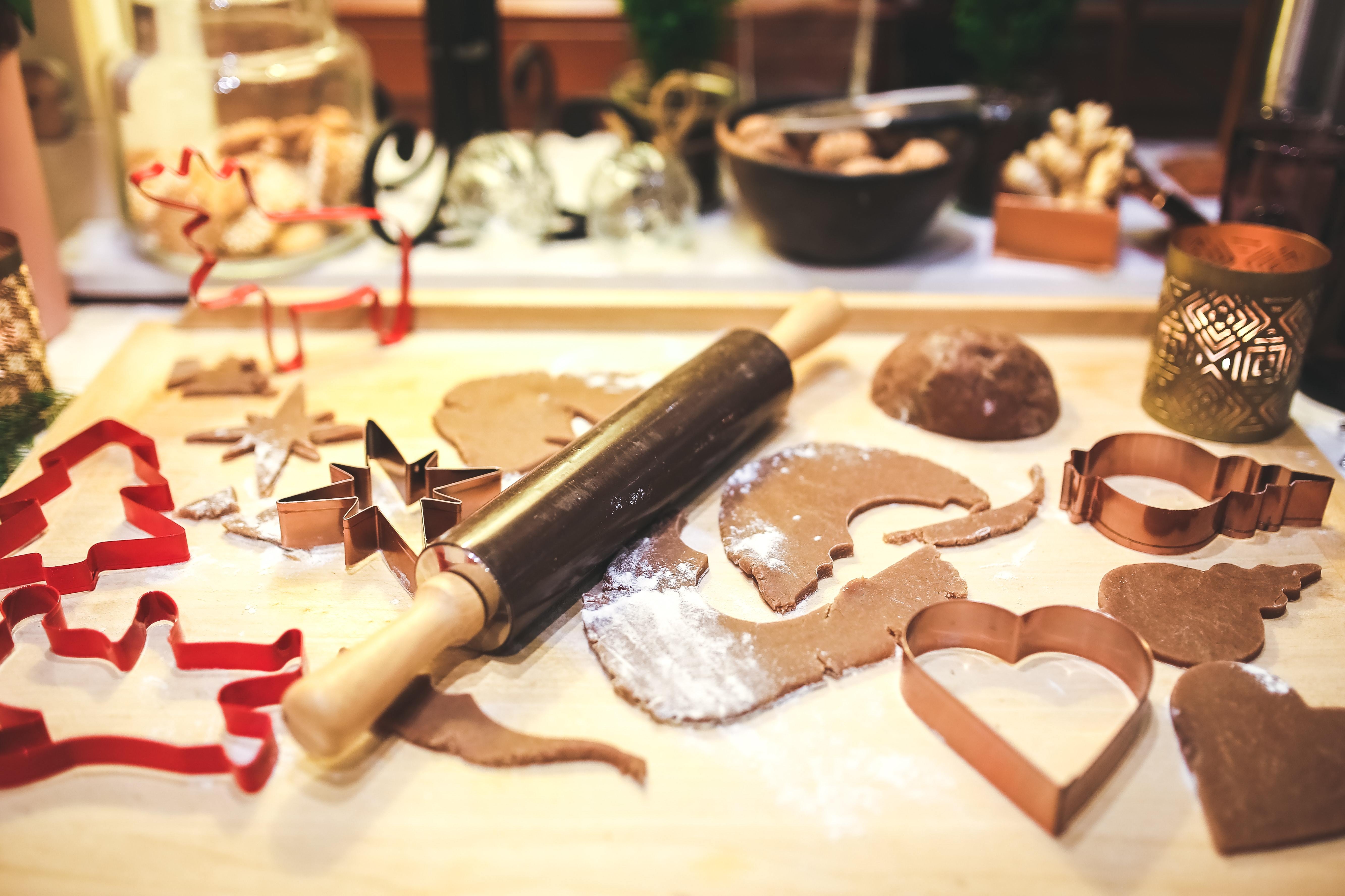 gingerbread cookies on on a counter top with cutting shapes and a rolling pin
